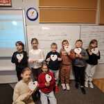 Dzieci stoją przy tablicy w klasie z papierowymi sercami w rękach..jpg