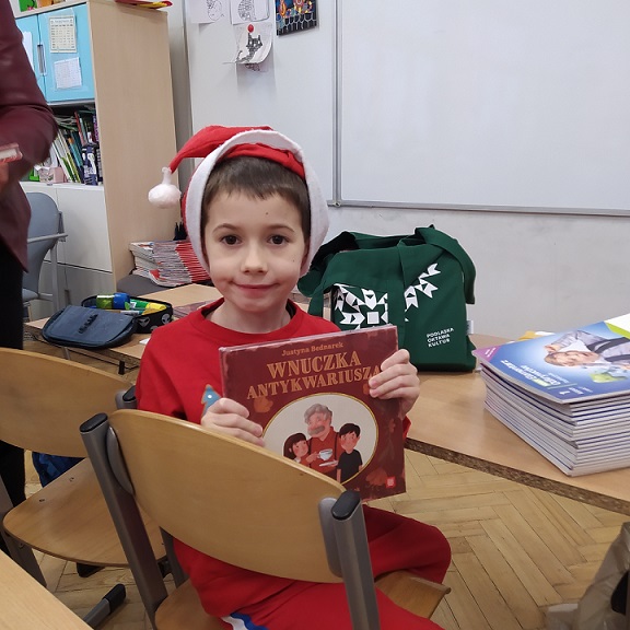 Uczeń w czapce Mikoołaja pokazuje książkę..jpg