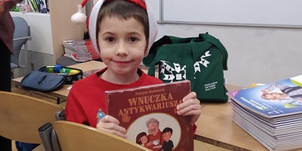Uczeń w czapce Mikoołaja pokazuje książkę..jpg