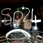 Zdjęcie uczniów w ciemności ze świetlistym napisem SP24