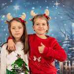 Dwie dziewczynki ubrane w bożonarodzeniowe stroje pozują do zdjęcia świątecznego