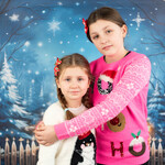 Dwie dziewczynki ubrane w bożonarodzeniowe stroje pozują do zdjęcia świątecznego