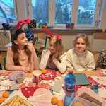 Trzy dziewczynki ubrane w świateczne stroje siedzą przy stole z jedzeniem..jpg