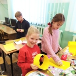 Dwie uczennice w klasie przygotowują papierowe_ żółte korony..jpg