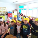 Uczniowie w papierowych i żółtych koronach na głowach pozują do zdjęcia w klasie..jpg