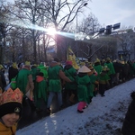 Grupa osób ubranych w zielone peleryny idzie w orszaku..jpg
