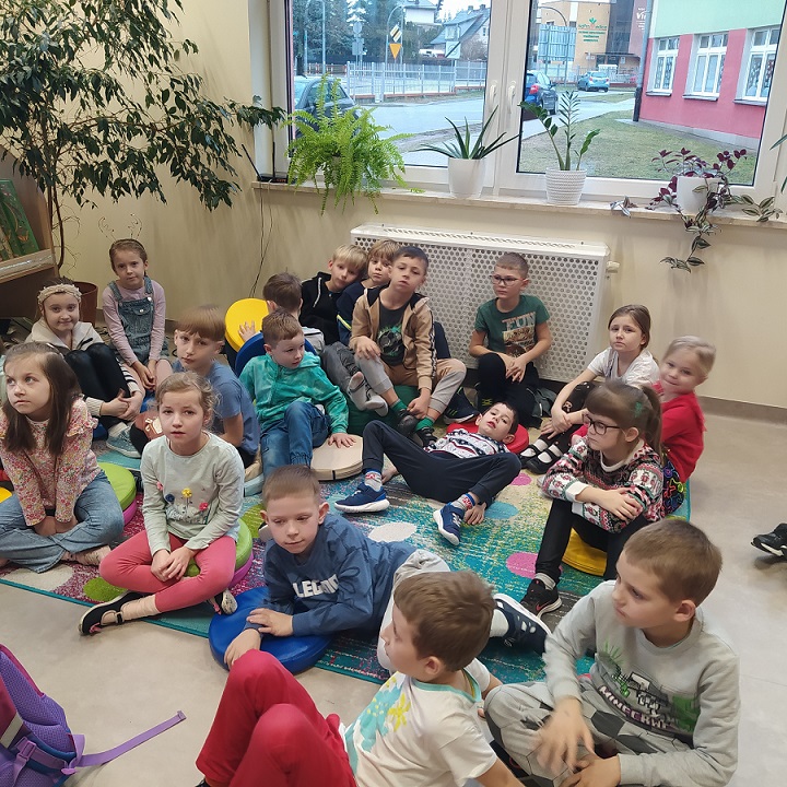 Grupa dzieci siedzi na kolorowym dywanie .jpg