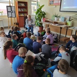 Nauczyciel czyta grupie uczniów siedzących na dywanie..jpg