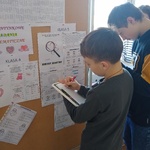 Uczniowie rozwiązują zagadki wywieszonych na tablicy.