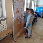 Uczniowie rozwiązują zagadki wywieszonych na tablicy.