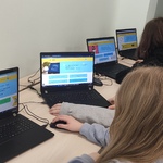 Uczniowie siedzą przed laptopami.jpg