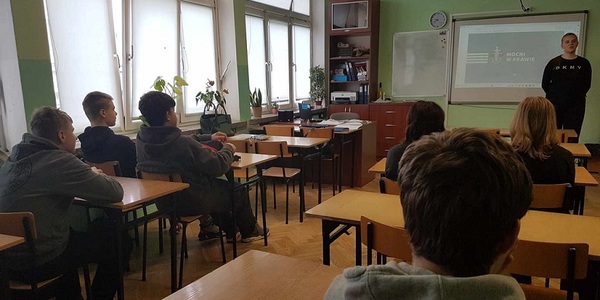 Uczniowie w klasie słuchają prelekcji studentki.