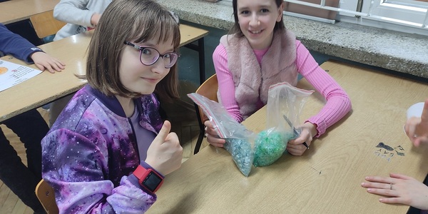 Dwie uczennice pokazują foliowe torebki z zielonym tworzywem..jpg