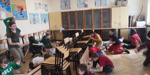 Uczniowie chowają się za krzesłami w sali lekcyjnej..jpg