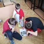 Troje uczniów wykonuje zadanie na podłodze w sali szkolnej..jpg