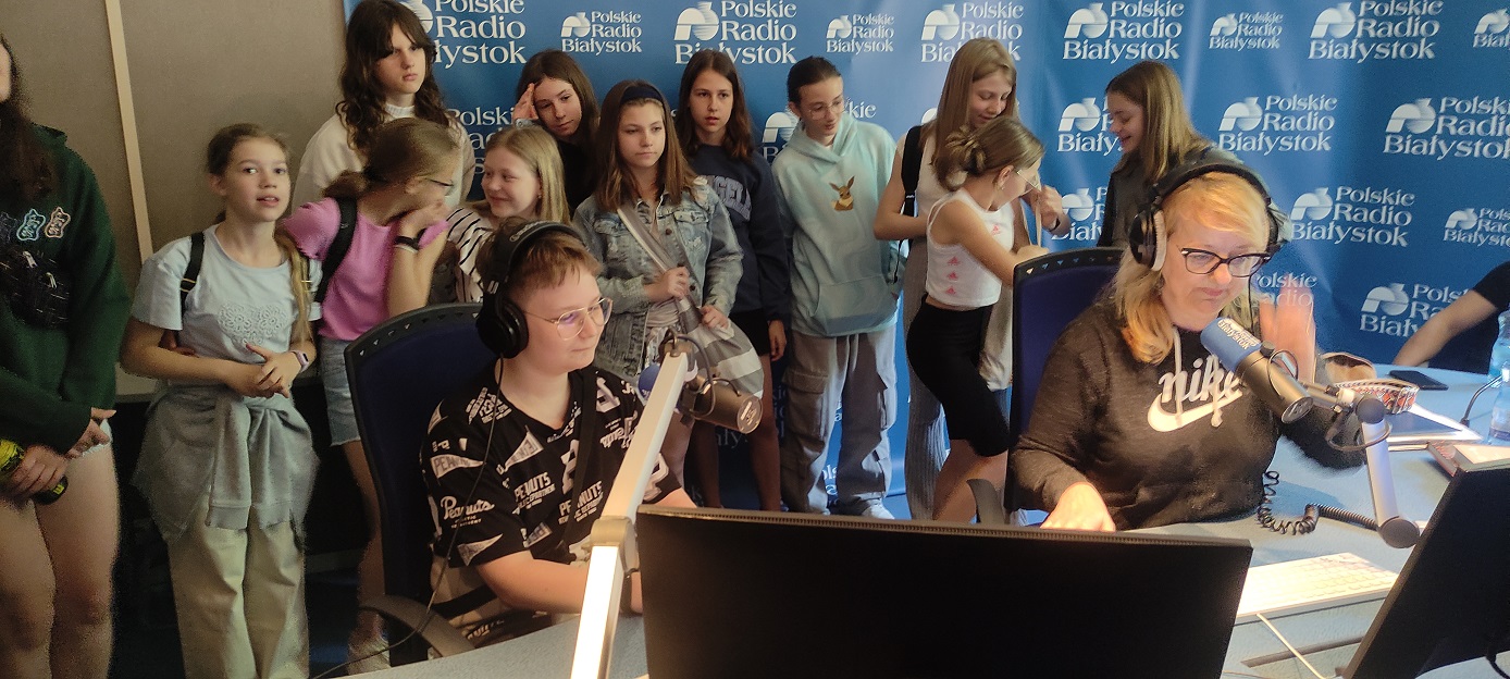 Grupa uczniów obserwuje w studiu nagrań radiowych Radia Białystok jak pani prowadzi audycję..jpg