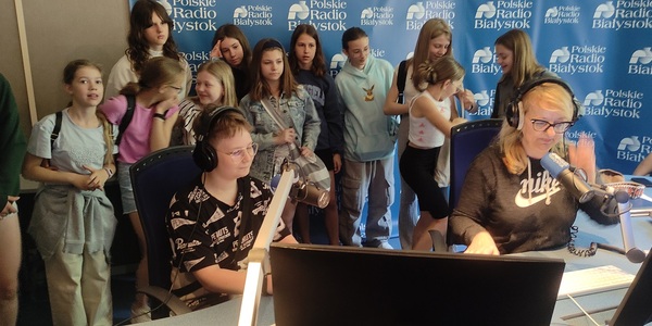 Grupa uczniów obserwuje w studiu nagrań radiowych Radia Białystok jak pani prowadzi audycję..jpg