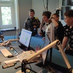 Grupa uczniów stoi w studiu nagrań radiowych.jpg