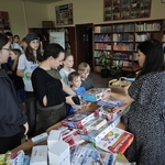 Dzieci stoją przed stoiskiem z grami planszowymi w bibliotece..jpg