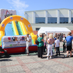 Grupa dzieci stojąca przed dmuchana zjeżdżalnią.