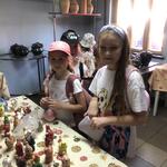 Dziewczynki stoją przy stole z kolorowymi glinanymi figurkami..jpg