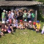 Grupa dzieci pozuje do zdjecia przy drewnianej szopie..jpg