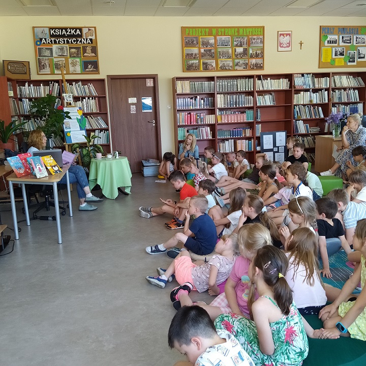 Pisarka czyta w bbliotece uczniom siedzącym na dywanie  fragment swojej książki.jpg