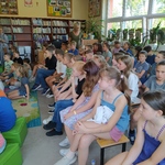 Uczniowie siedzą na krzesłach w bibliotece i słuchają pisarki..jpg