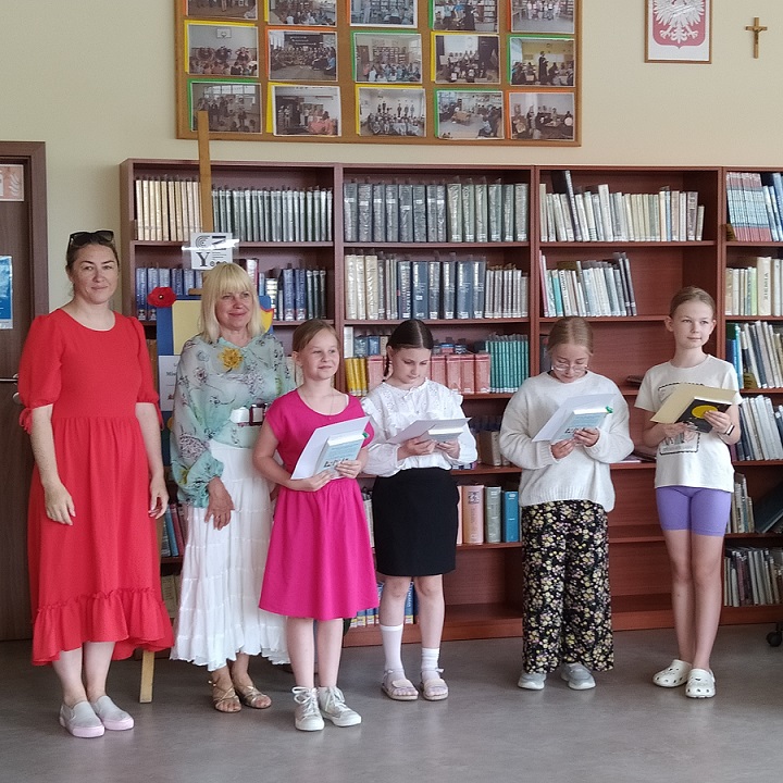 Cztery uczennice stoją z książkami w bibliotece obok dwóch pań..jpg