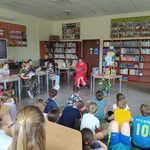 Nauczycielka czyta książkę uczniom siedzącym na podłodze w bibliotece..jpg