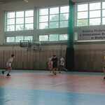 Grupa uczniów gra w piłkę nożną na sali sportowej. W tle napis SP24.jpg