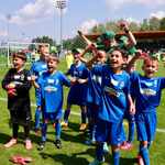 Ucniowie w niebieskich strojach sportowych cieszą się na boisku..jpg