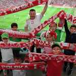 Grupa uczniów razem z trenerem trzyma szaliki biało-czerwone z napisem Polska na stadionie narodowym..jpg