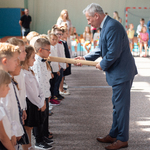 Pan dyrektor dotyka dużą kredką ramienia ucznia- ceremonia pasowania.