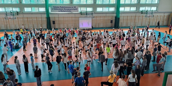 Duża grupa uczniów ćwiczy na hali gimnastycznej..jpg