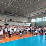 Duża grupa uczniów ćwiczy na hali gimnastycznej.jpg