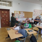 nauczyciel prezentuje książkę uczniom siedzącym w ławkach szkolnych..jpg
