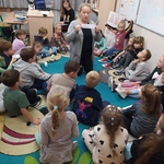 Nauczycielka pokazuje uczniom siedzącym w kręgu napis Oczarować.jpg