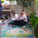 Uczennice czytają książki siedząc na kolorowym dywanie.jpg
