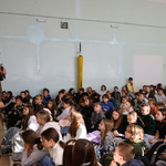  Mężczyzna przebrany w strój średniowieczny mówi do dużej grupy uczniów siedzących na sali.