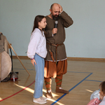 Dziewczyna stoi przy mężczyźnie ubranym w strój średniowieczny.