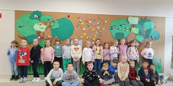Grupa dzieci stoi na tle drzew z kartonu.jpg