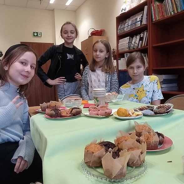 Uczennice siedzą przy stole z babeczkami.jpg