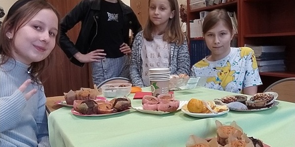 Uczennice siedzą przy stole z babeczkami.jpg