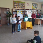 Dwie dziewczynki w bibliotece stoją z kartkami w rękach .jpg