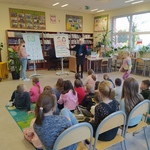 Uczniowie siedzą w bibliotece i patrzą na panią pokazującą ilustracje na flipcharcie..jpg