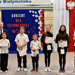 Grupa uczniów razem z dyrektorem pozuje do zdjęcia z dyplomami.