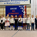 Grupa dzieci ubrana na galowo śpiewa pieśni.
