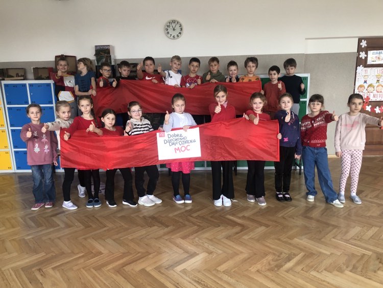 Grupa uczniów trzyma czerwoną wstęgę.jpg