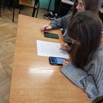 Dziweczyny w ławce rozwiązują zadania na kartce.jpg
